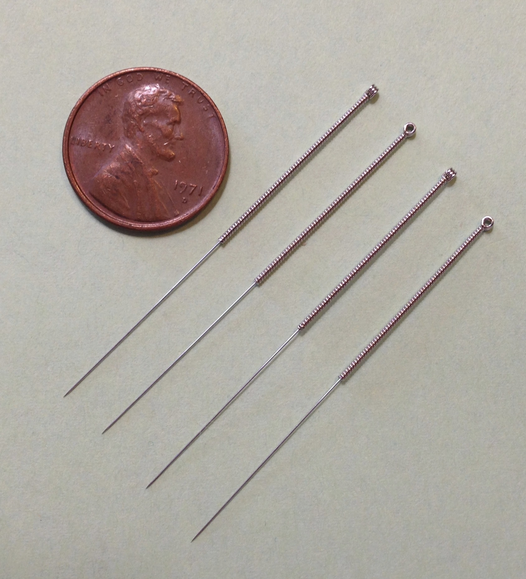 Acupuncture needles size compared to a penny